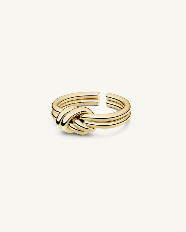A polished stainless steel ring in 14k gold from Waldor & Co. One size. The model is Dual Knot Ring.