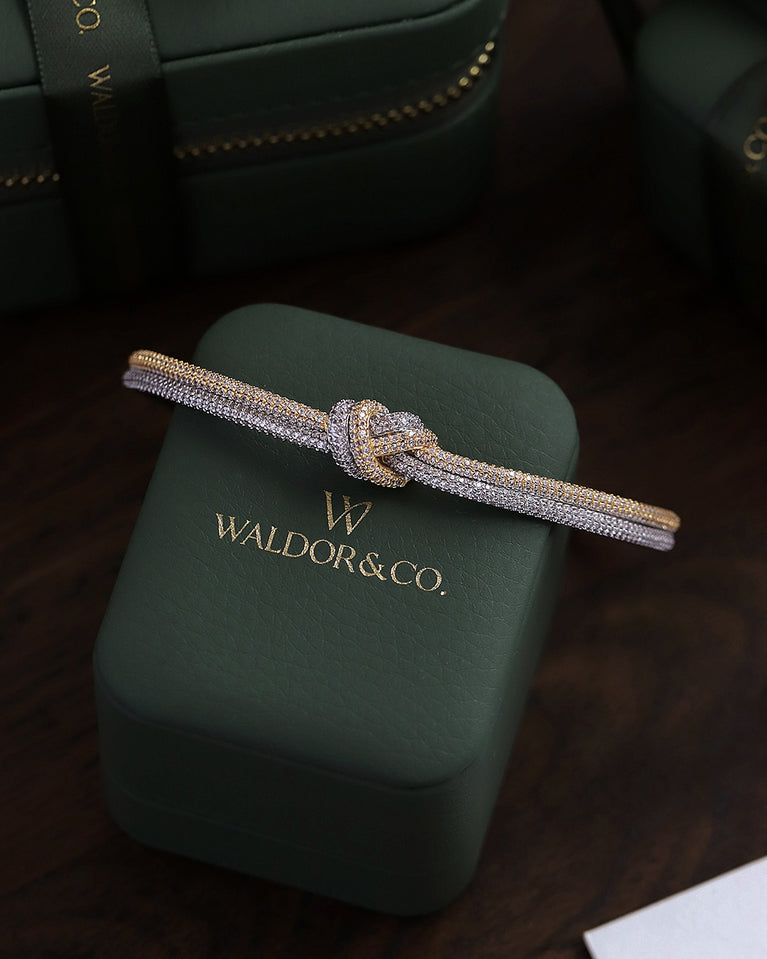 A Bangle in 14k-gold plated and silver polished copper from Waldor & Co. One size. The model is Dual Knot Bangle Pavè.