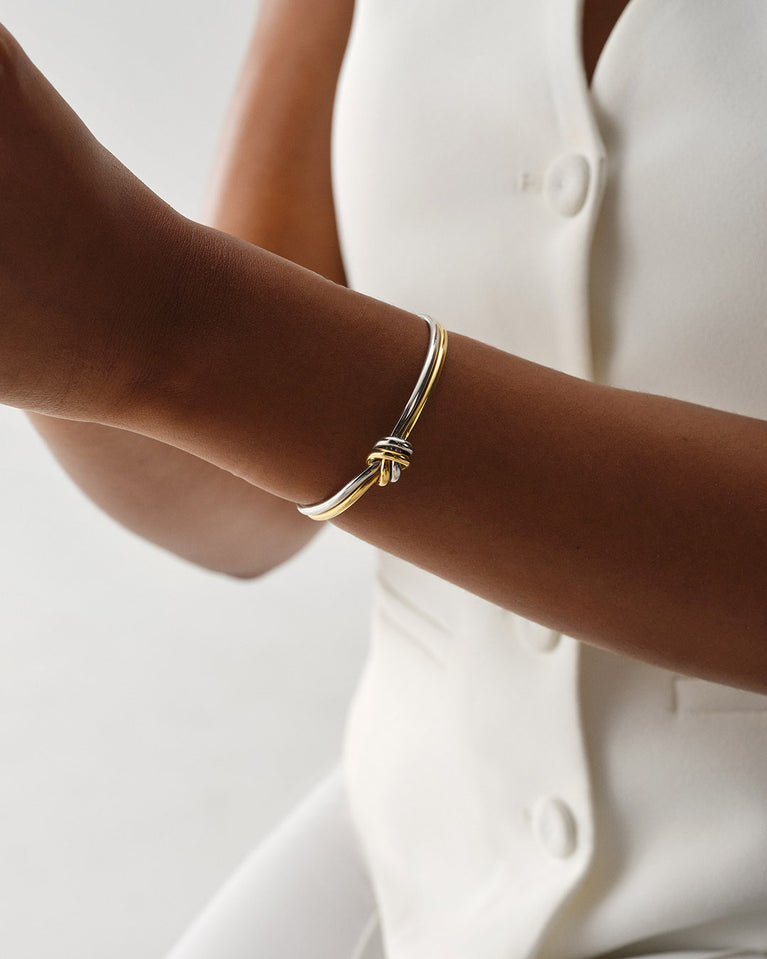 A Bangle in 14k-gold plated and silver polished 316L stainless steel from Waldor & Co. One size. The model is Dual Knot Bangle Polished.