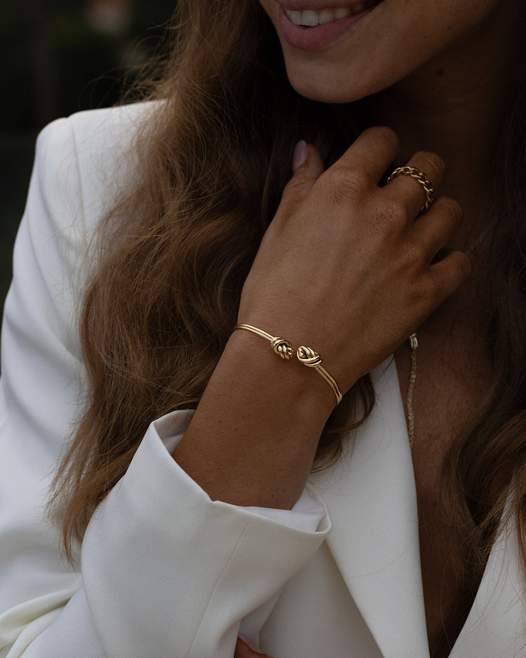 A Bangle in 14k-gold plated 316L stainless steel from Waldor & Co. One size. The model is Dual Knot Twin Bangle Polished.