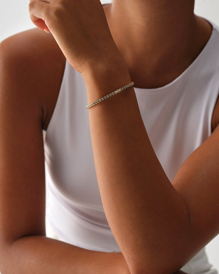 A polished stainless steel bangle in 14k gold from Waldor & Co. One size. The model is Grace Bangle Polished.