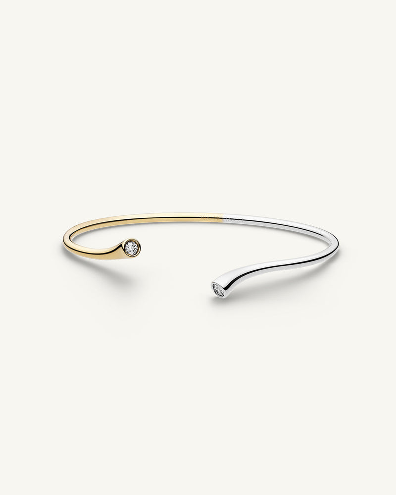 A polished stainless steel bangle in 14k gold from Waldor & Co. One size. The model is Delight Bangle.