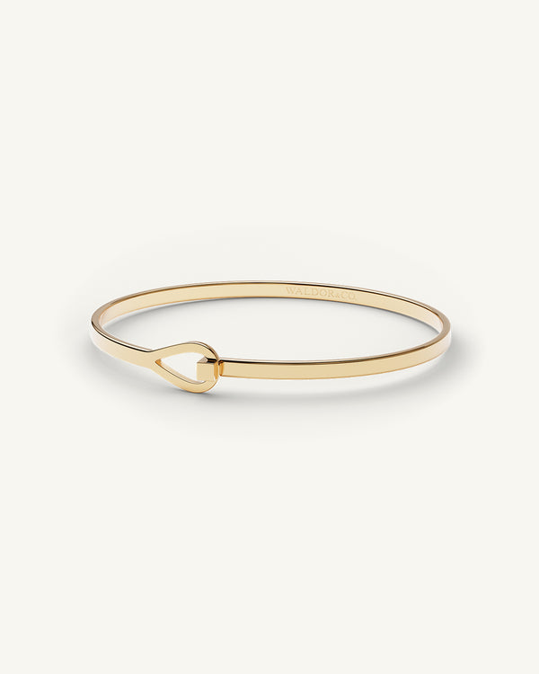 A Bangle Bracelet in 14k gold-plated from Waldor & Co. The model is Signature Bangle Polished Gold