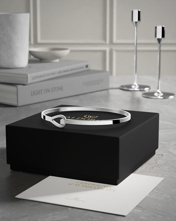 A polished stainless steel bangle in silver from Waldor & Co. The model is Signature Bangle Polished