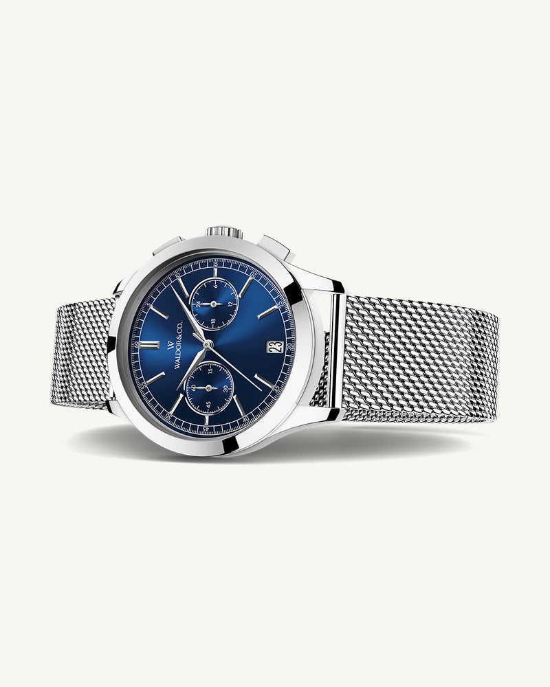 En rund herrklocka i rodiumpläterat silver från WALDOR & CO. med blå sunray urtavla och en sekundvisare. Seiko urverk. Modellen är Chrono 39 Sardinia 39mm. 
