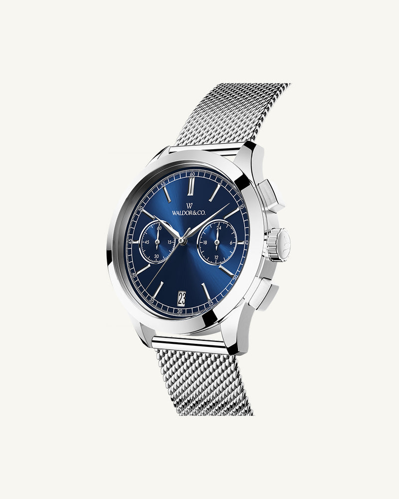 En rund herrklocka i rodiumpläterat silver från WALDOR & CO. med blå sunray urtavla och en sekundvisare. Seiko urverk. Modellen är Chrono 39 Sardinia 39mm. 