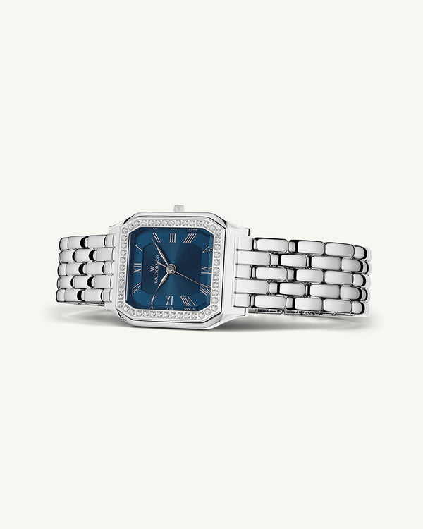 A square womens watch in Rhodium-plated 316L stainless steel from Waldor & Co. with dark blue dial. Bezel with premium crystals. Diamond Cut Sapphire Crystal glass dial. Seiko movement. The model is Eternal 22 Bellagio Pavè.
