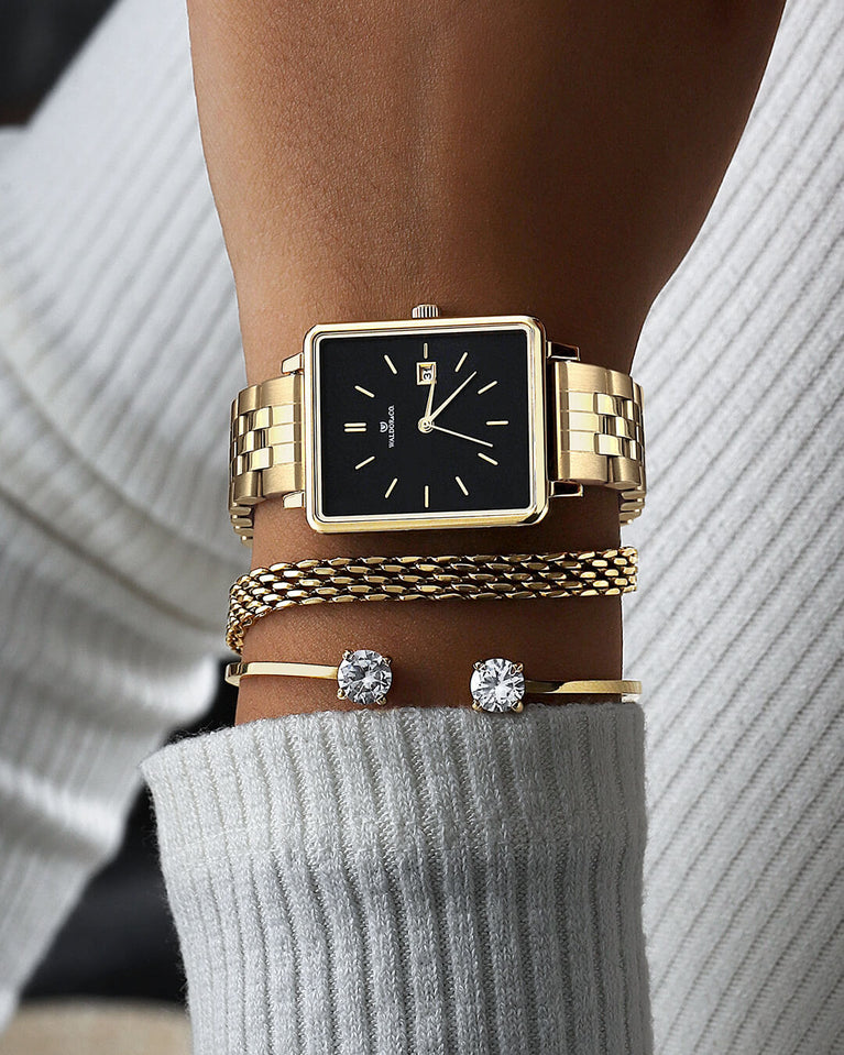A square womens watch in silver and 14k gold from Waldor & Co. with black sunray dial and a second hand. Seiko movement. The model is Delight 32 Chelsea 28x32mm.