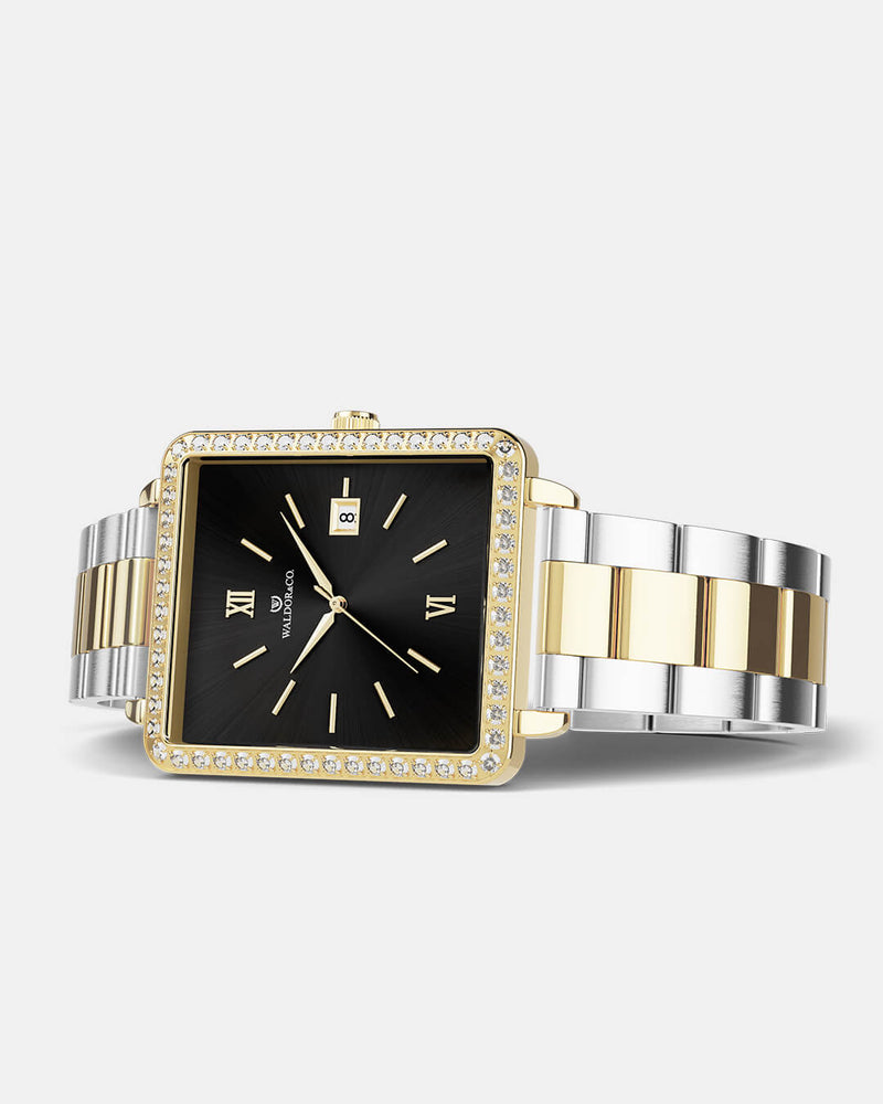A square womens watch in 22k gold-plated 316L stainless steel with stones from WALDOR & CO. with black sunray dial and a second hand. Seiko VJ22 movement. The model is Delight 32 Mayfair Ltd. Edition 28x32mm. 