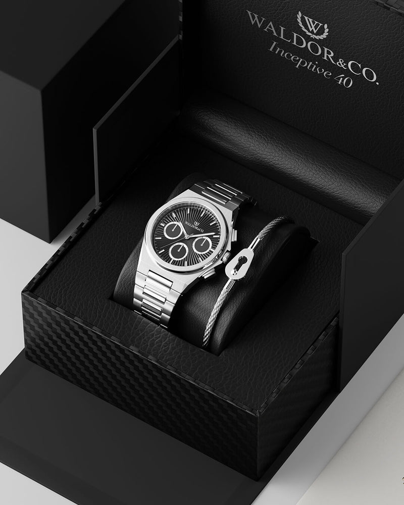 En rund herrklocka i rodiumpläterat silver från WALDOR & CO. med svart sunray urtavla och självlysande visare. Seiko urverk. Modellen är Inceptive 40 Azores.